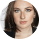 Close-up portrait of a woman with dark hair and subtle makeup, looking at the camera against a neutral background.